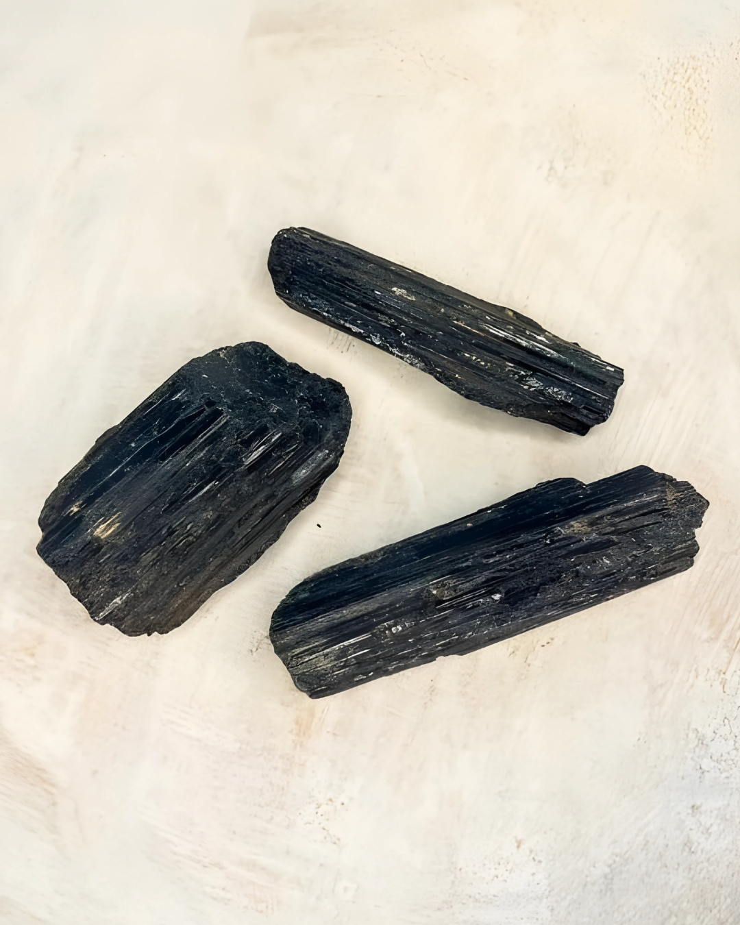 Three black crystals on a light beige background