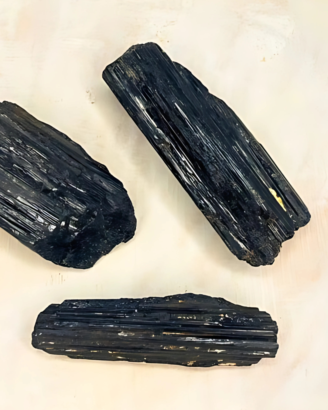 Three black crystals on a light beige background