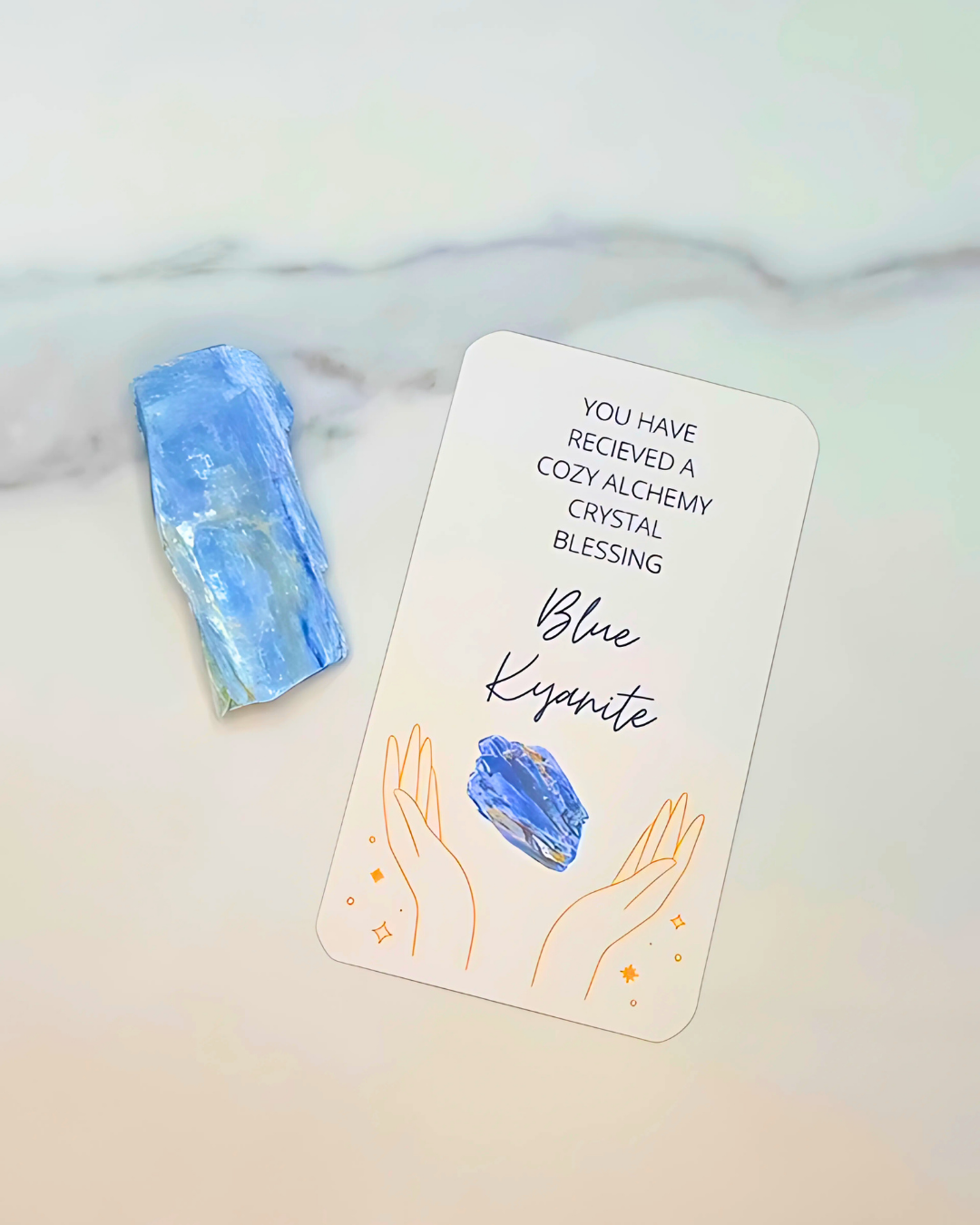 Blue Kyanite crystal with a blessing card on a marble surface