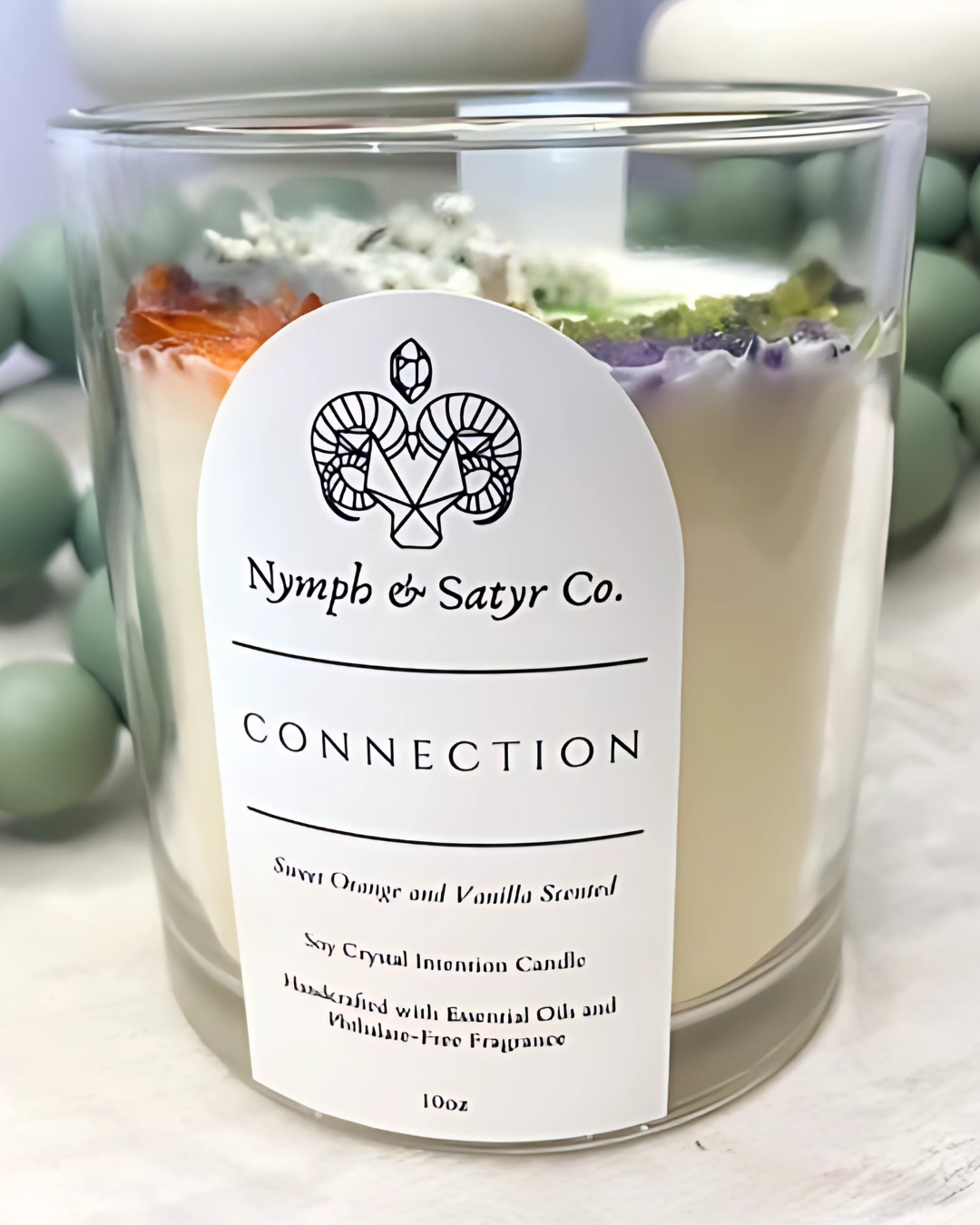 Candle with 'Nymph & Satyr Co.' label on a light background