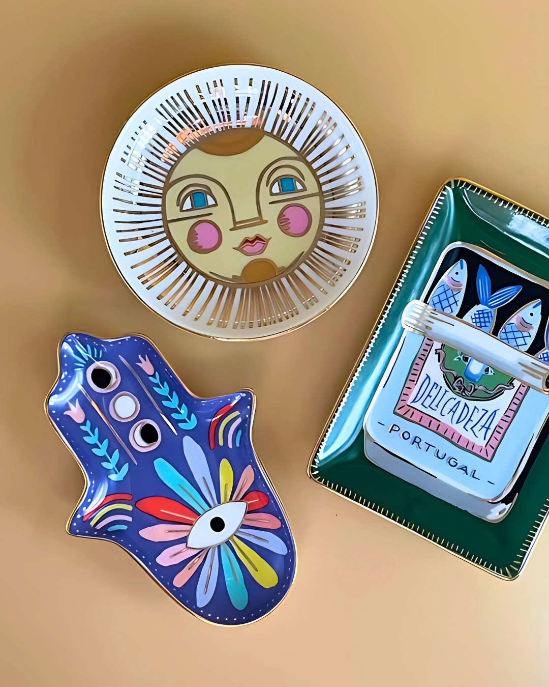 Three decorative items on a beige background: a face-shaped mirror, a colorful Hamsa hand, and a small box with owl design.