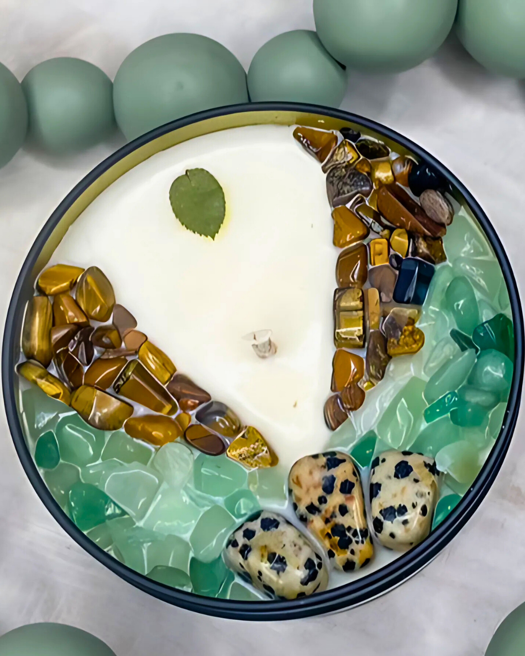 Decorative bowl with stones and a leaf on a white surface