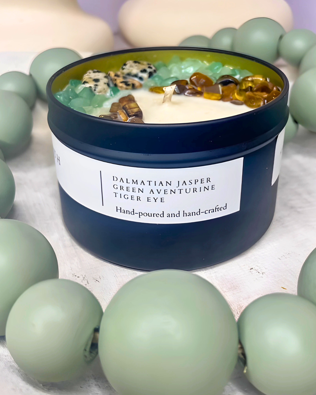 Candle in a blue container with decorative stones on a light background