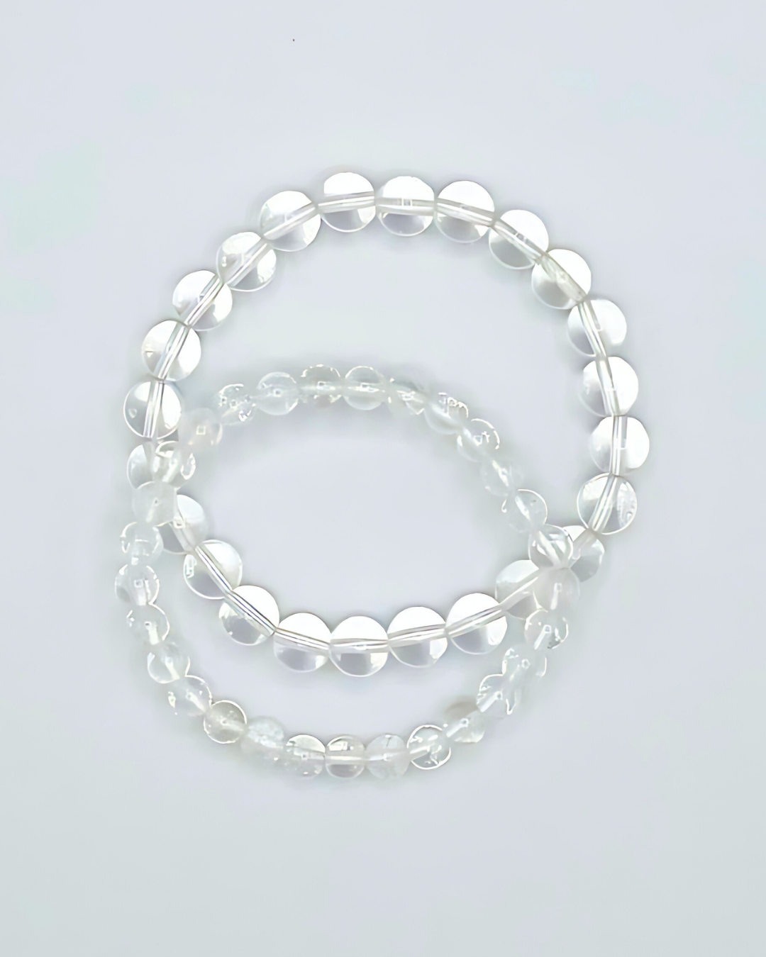 Two clear beaded bracelets on a light gray background
