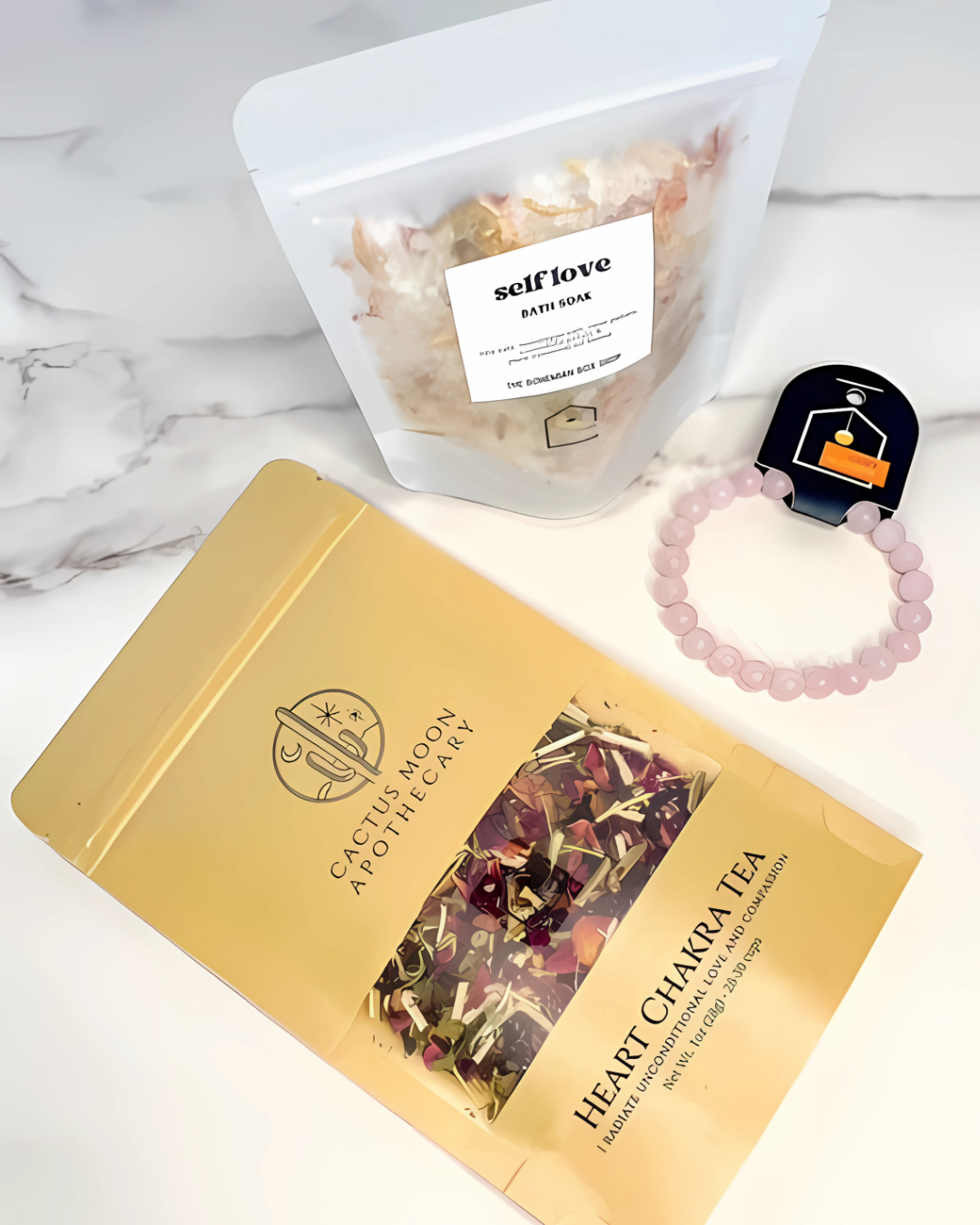 Heart Chakra Tea packaging with a container labeled 'self love' and a bracelet on a marble surface.
