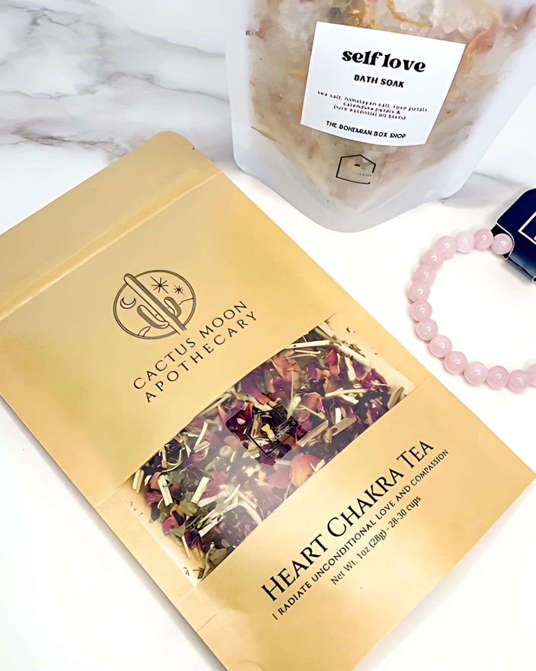 Cactus Moon Aromatherapy Heart Chakra Tea package with a bath soap bar and bracelet on a marble surface.