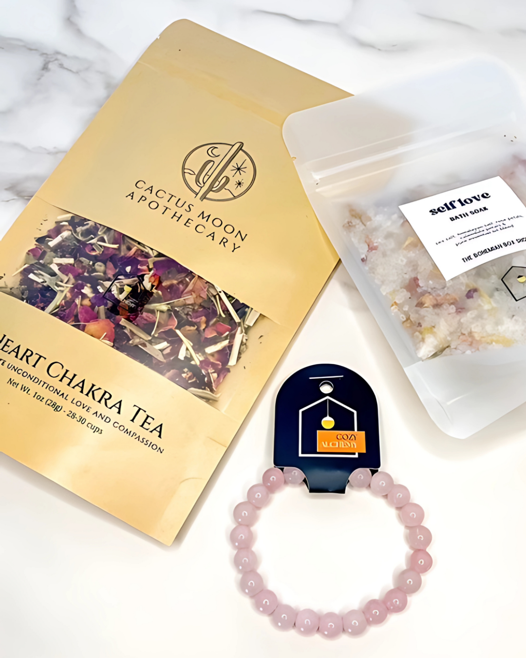 Cactus Moon Apothecary heart chakra tea package with a bracelet and small bag on a marble surface.