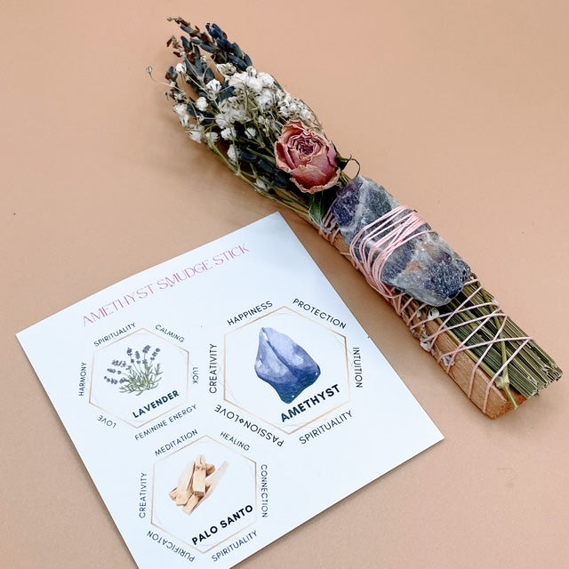 Aromatherapy smudge stick with dried flowers and a card explaining its properties on a beige background