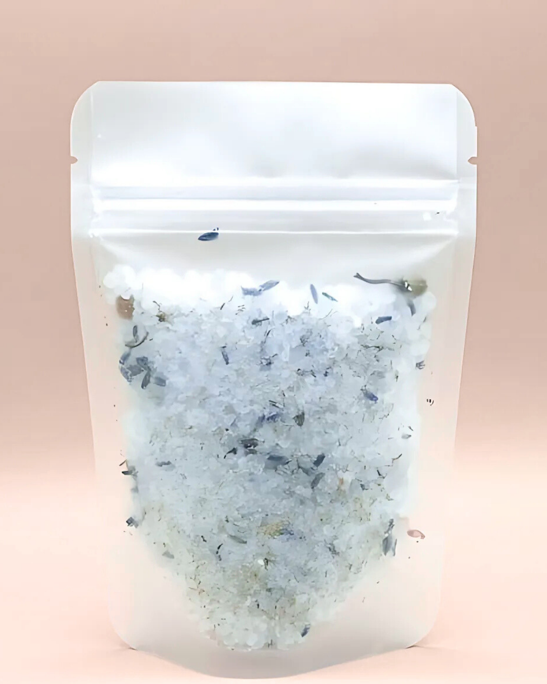 Clear packaging with a white lid containing a bath salt mix on a pink background