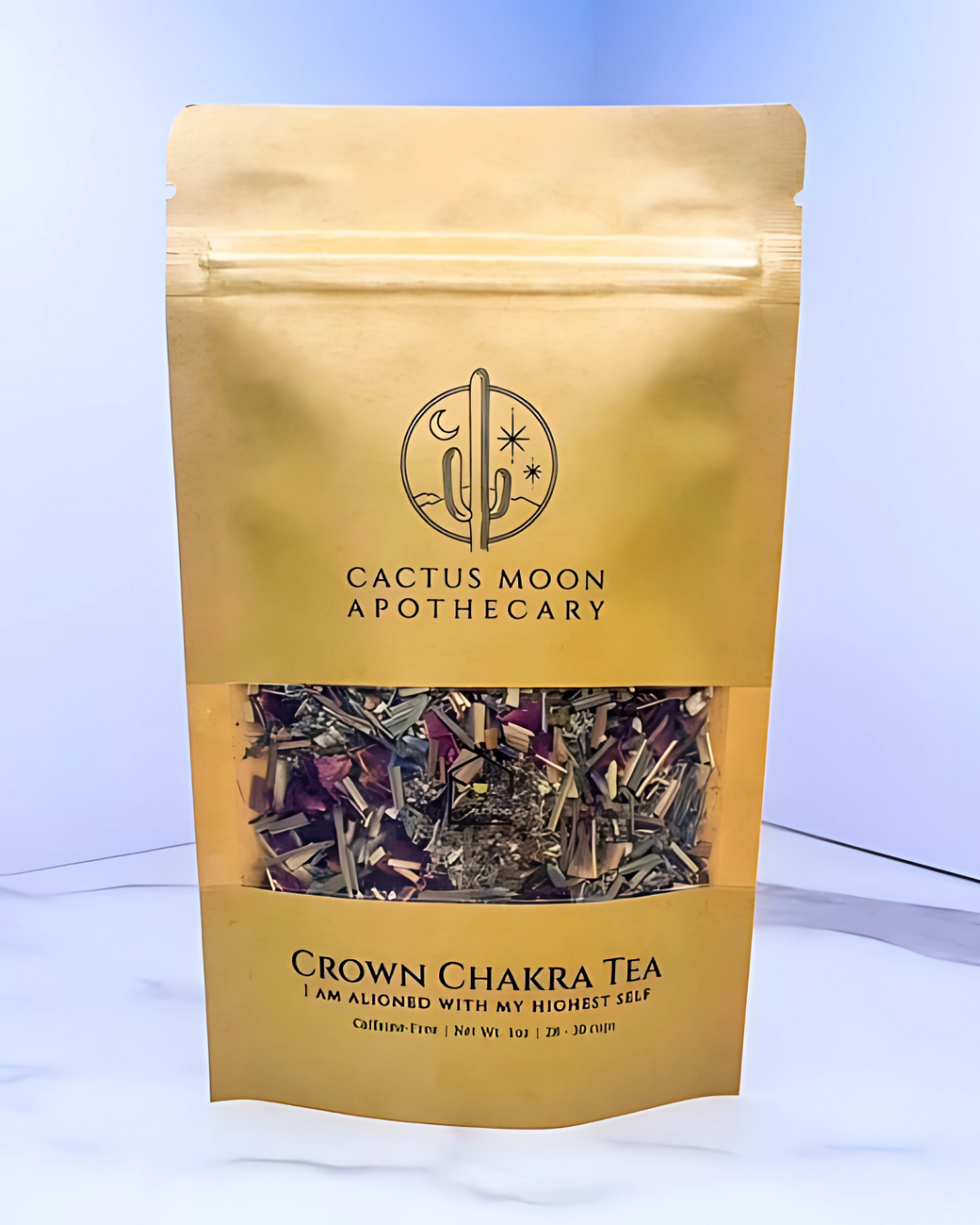 Gold packaging of Crown Chakra Tea from Cactus Moon Apothecary on a light blue background