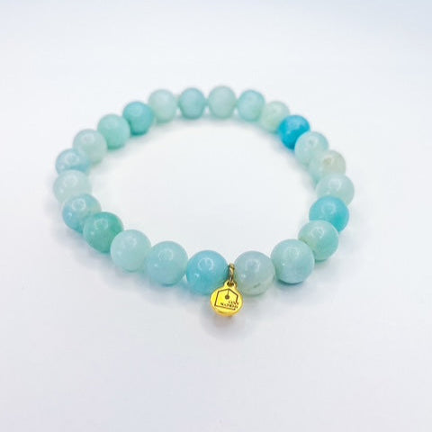 Turquoise beaded bracelet with a gold charm on a white background