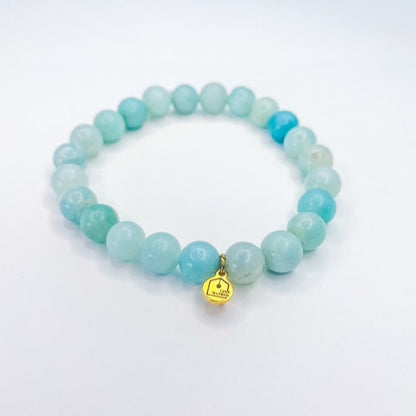 Turquoise beaded bracelet with a gold charm on a white background