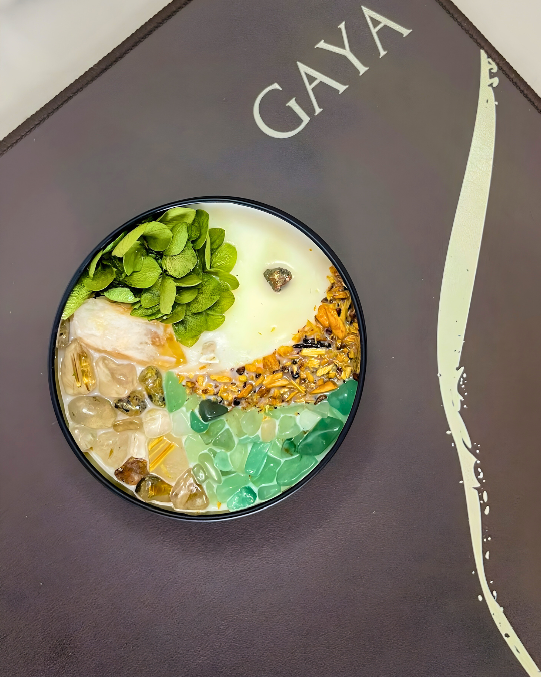 Colorful dessert with green, white, and orange layers on a dark surface with 'GAYA' branding.