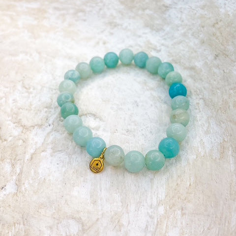 Beaded bracelet with a gold heart charm on a textured white surface