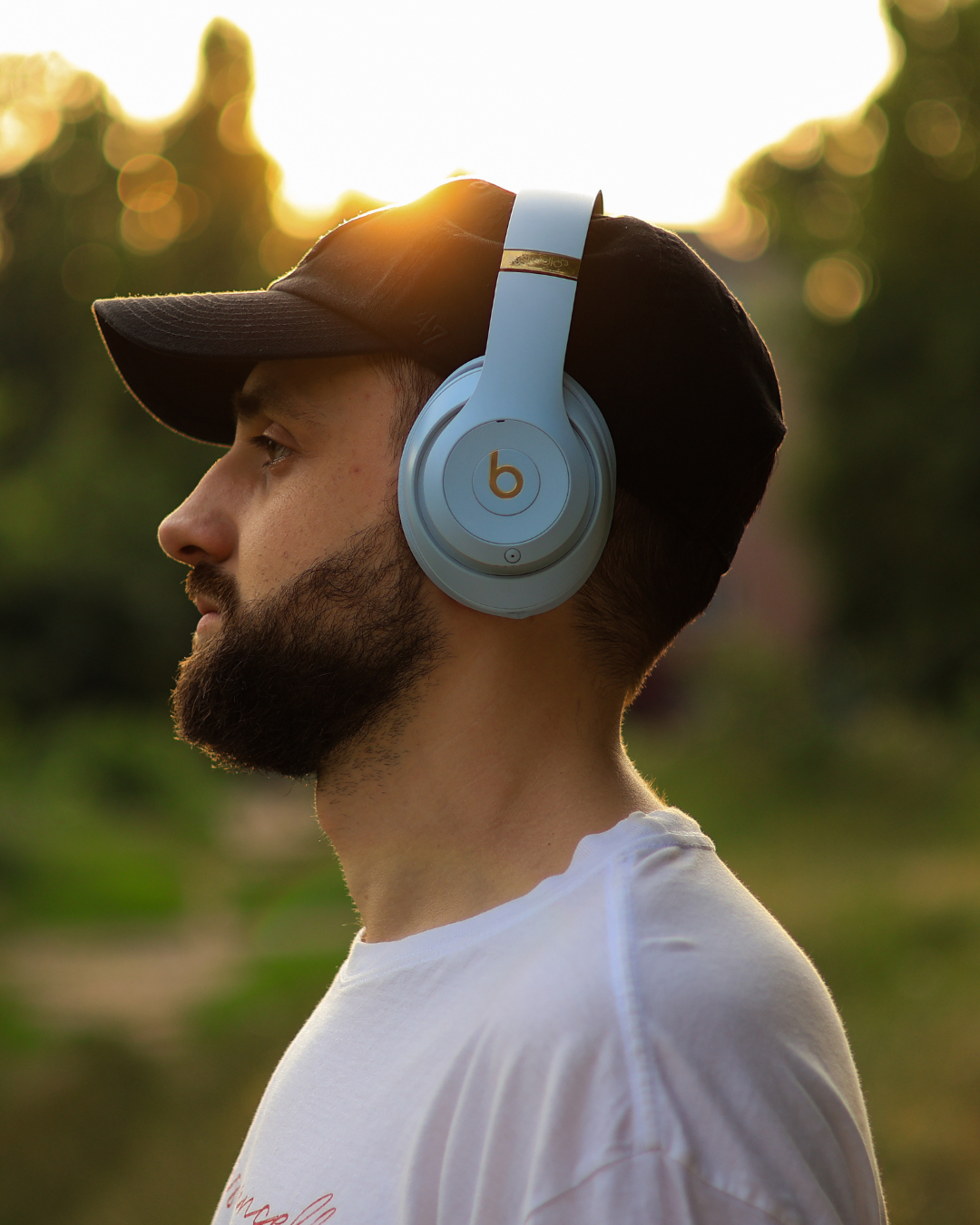 Man wearing Beats headphones outdoors with a blurred natural background