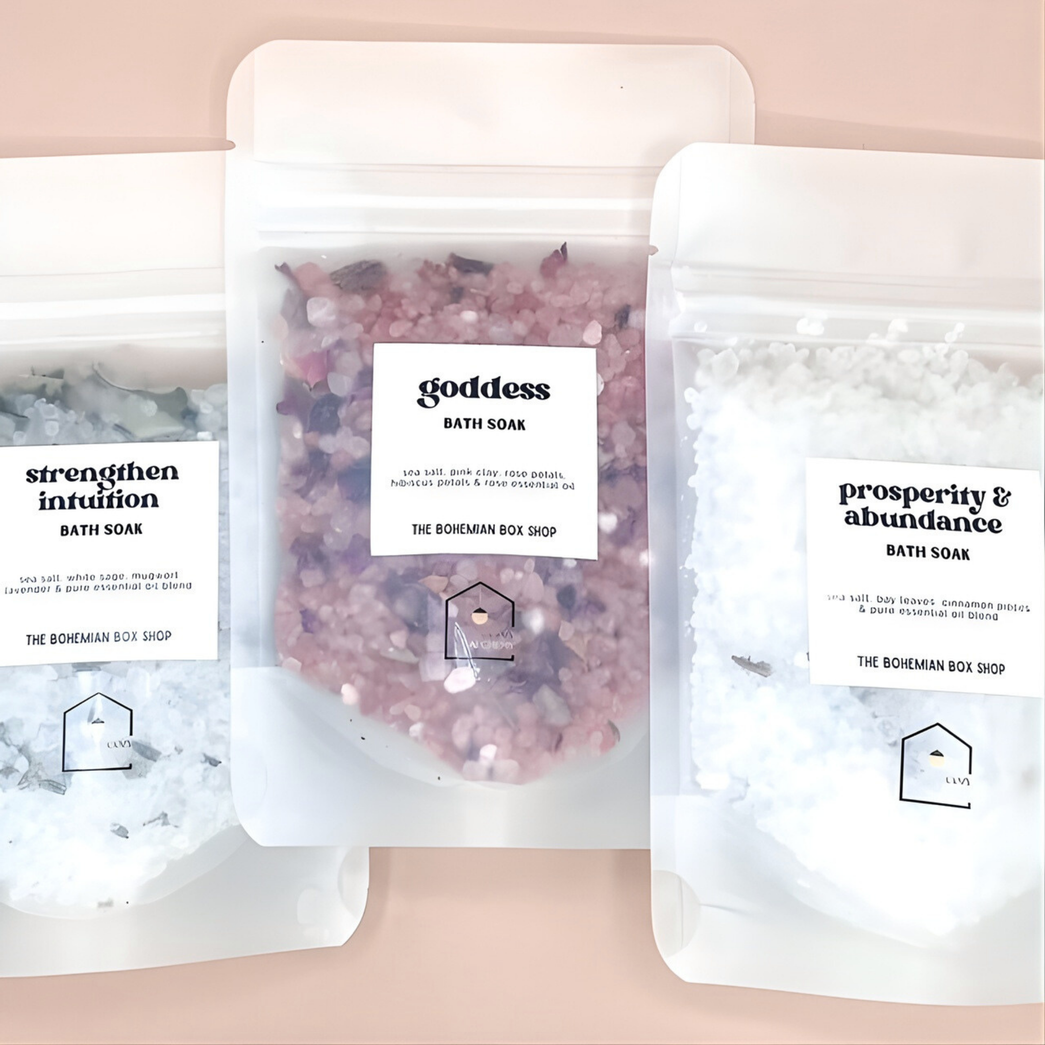 Three bags of bath soaks with labels on a pink background