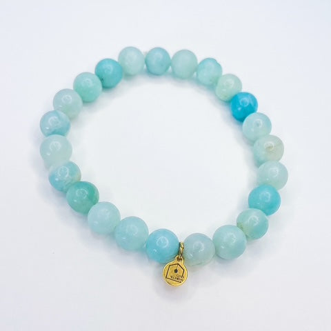Turquoise beaded bracelet with a gold tag on a white background