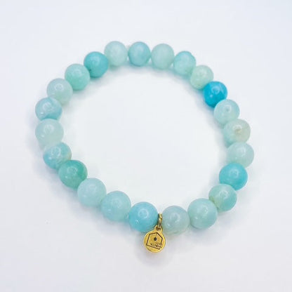 Turquoise beaded bracelet with a gold tag on a white background