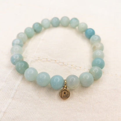 Light blue beaded bracelet with a gold tag on a white background