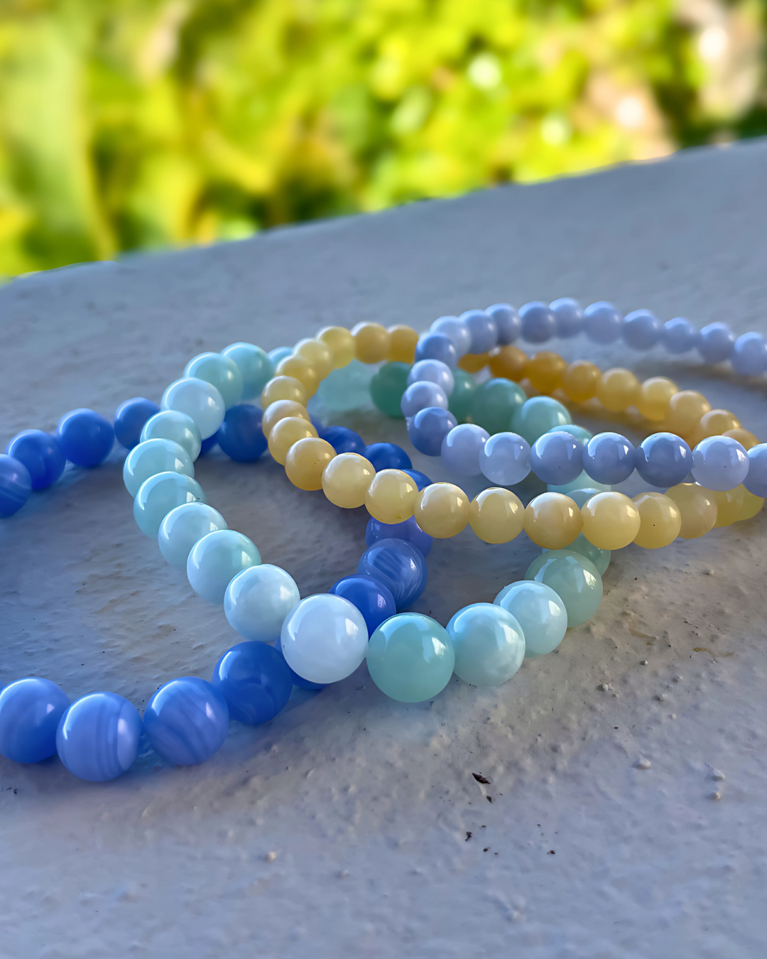 Set of colorful beaded bracelets on a textured surface with a blurred natural background