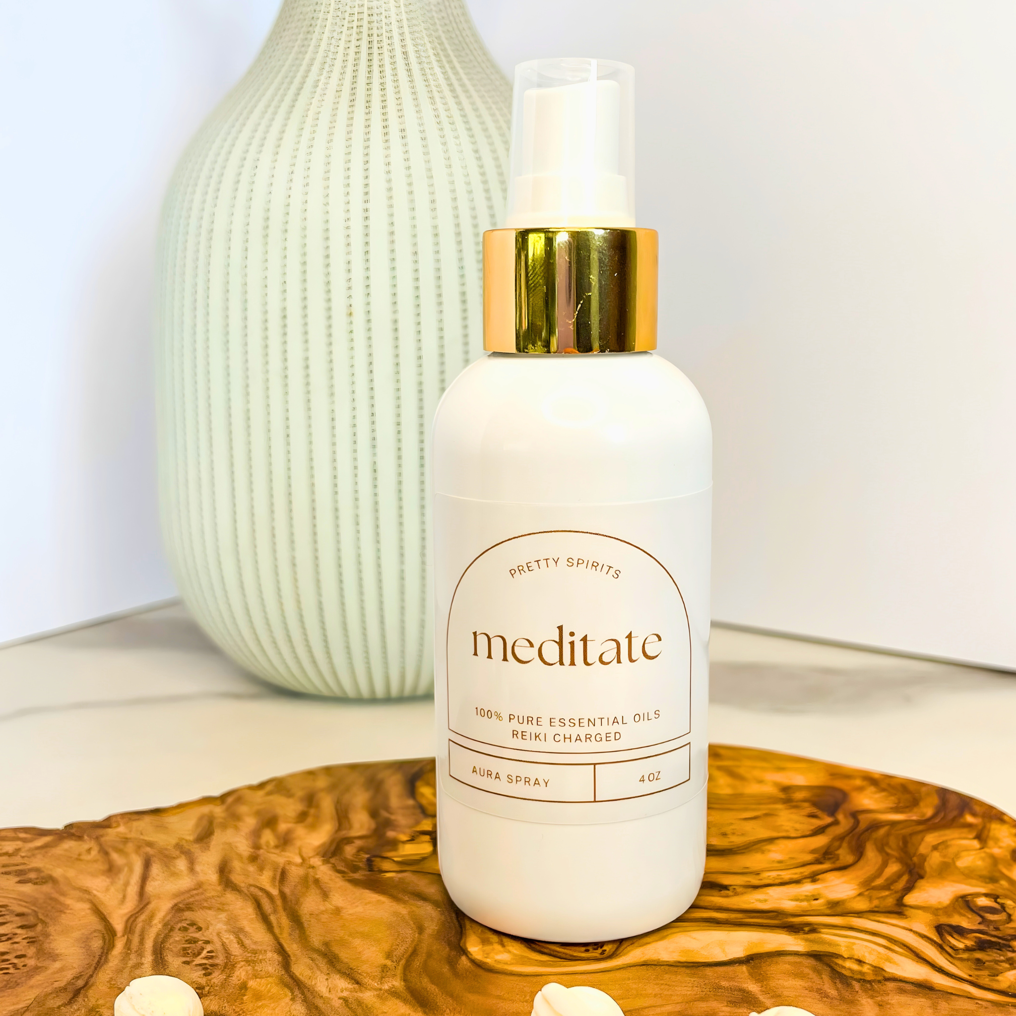 White bottle with gold cap labeled 'meditate' on a wooden surface with a light background