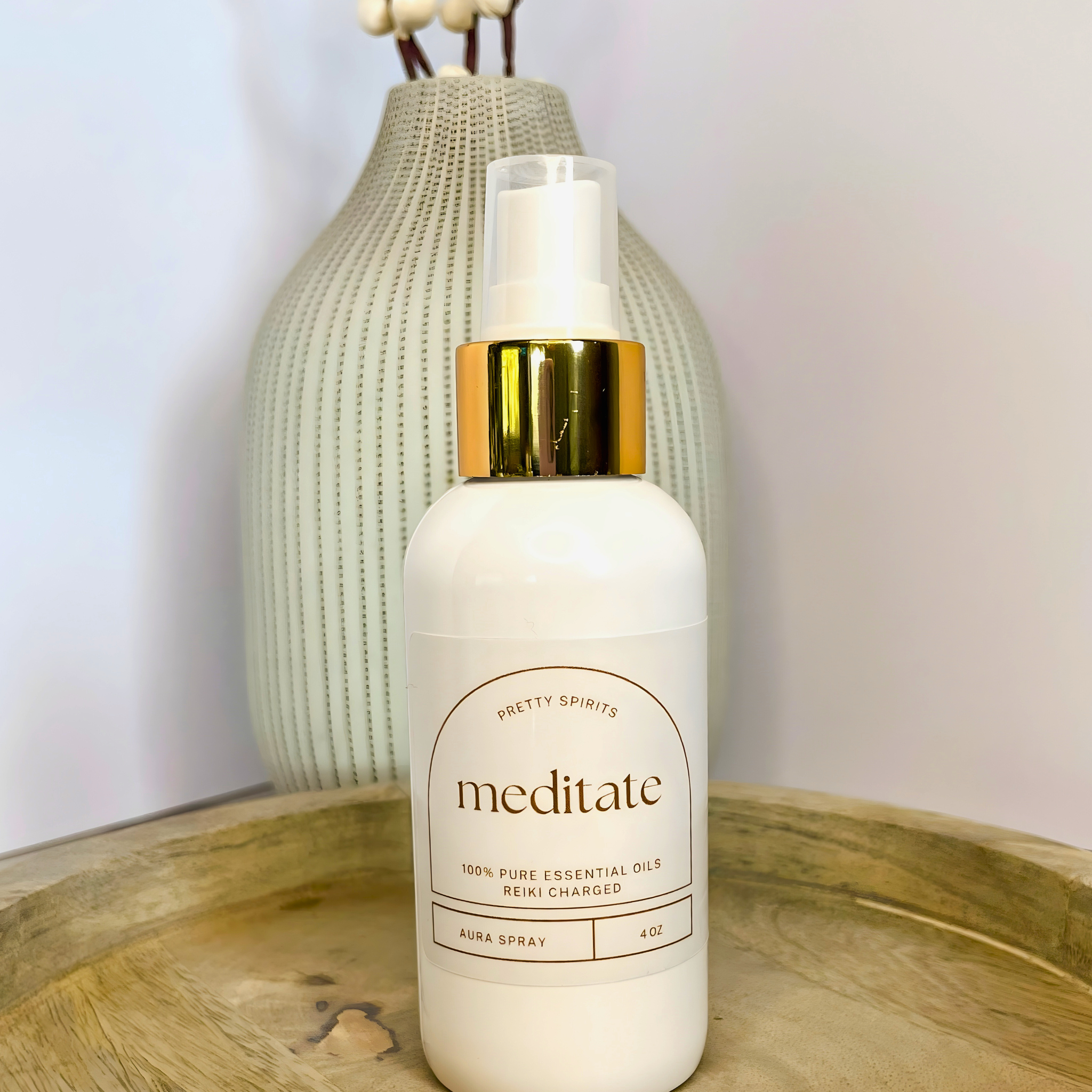 White bottle labeled 'meditate' with gold cap on a wooden tray