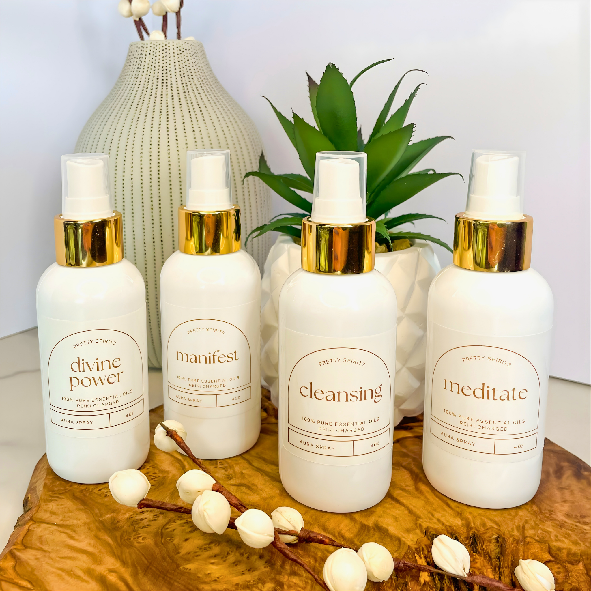 Four white bottles with gold caps on a wooden surface with decorative elements.