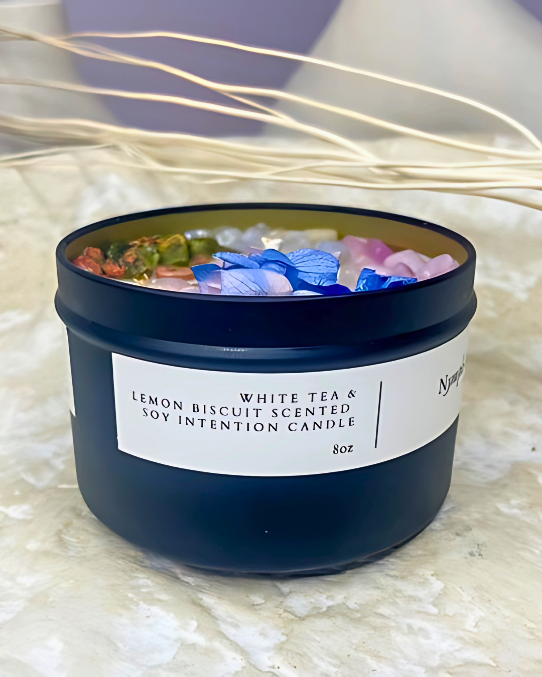 Candle with colorful flower petals and a label on a textured surface