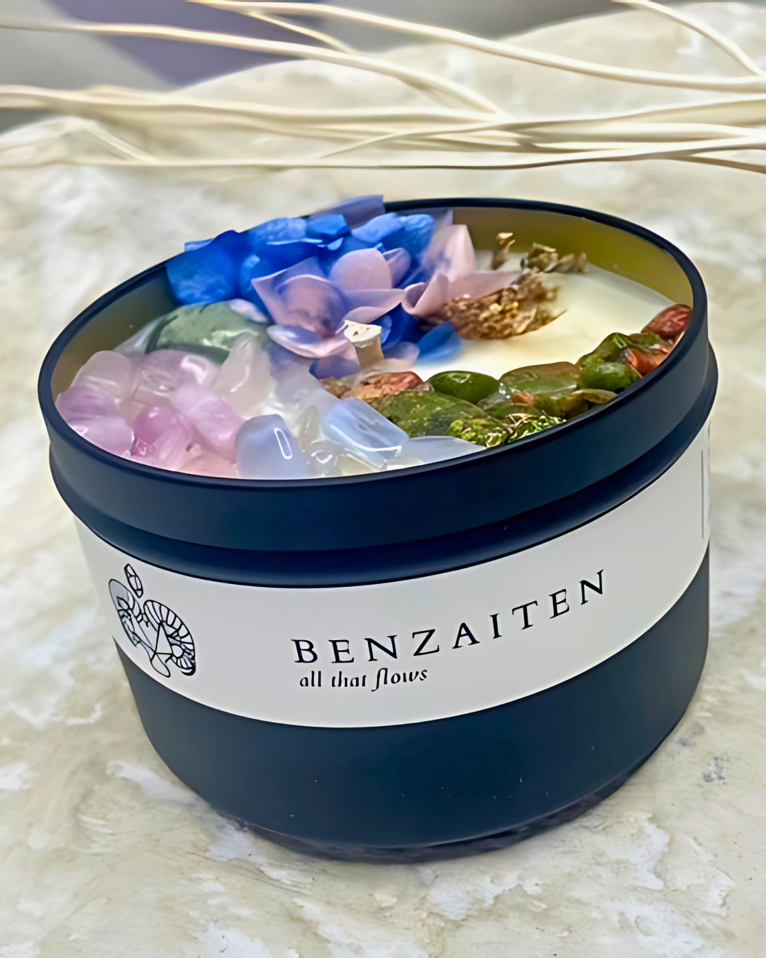 Benzaiten candle with floral design and natural elements on a textured surface