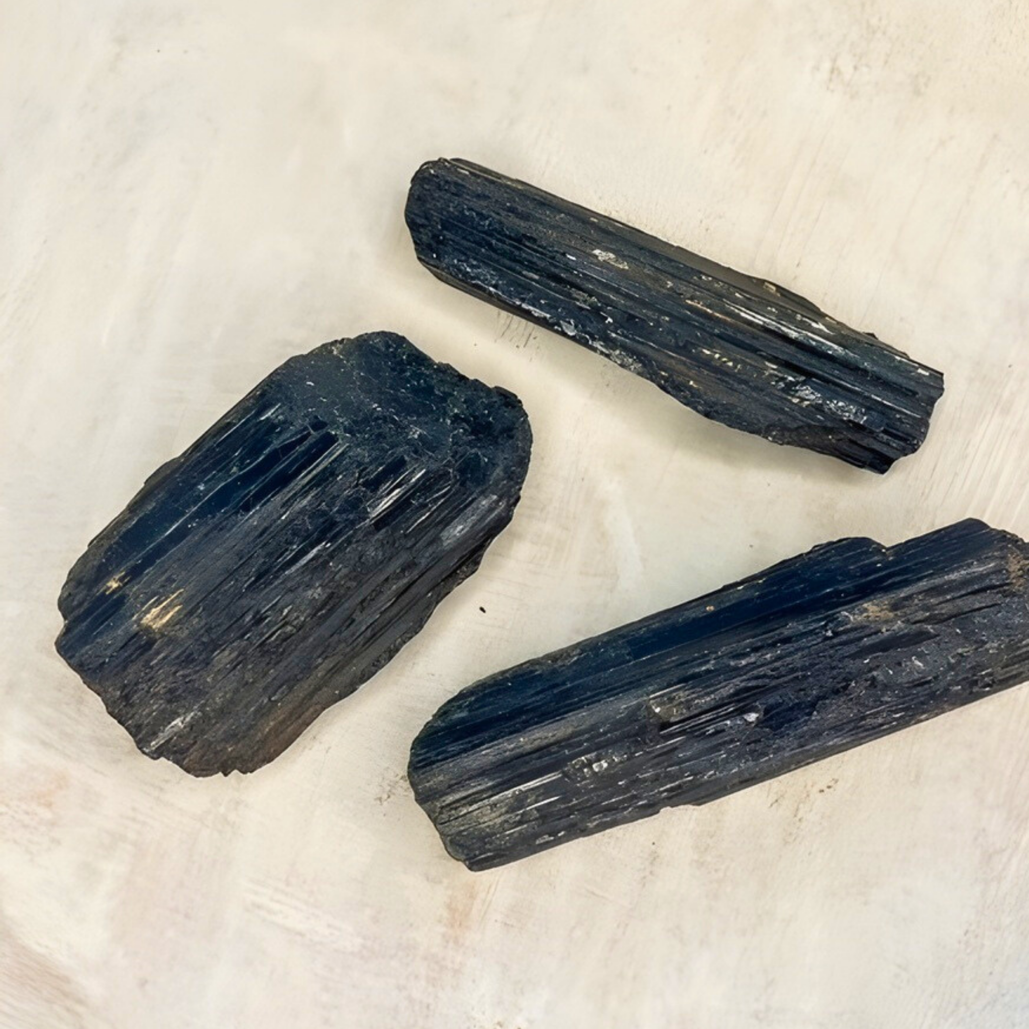 Three black crystals on a light beige background