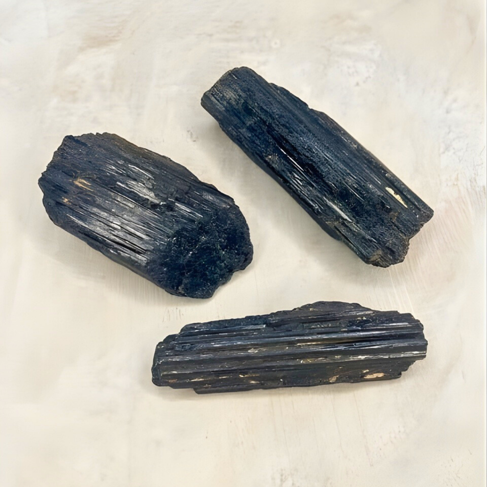 Three dark blue crystals on a light beige surface