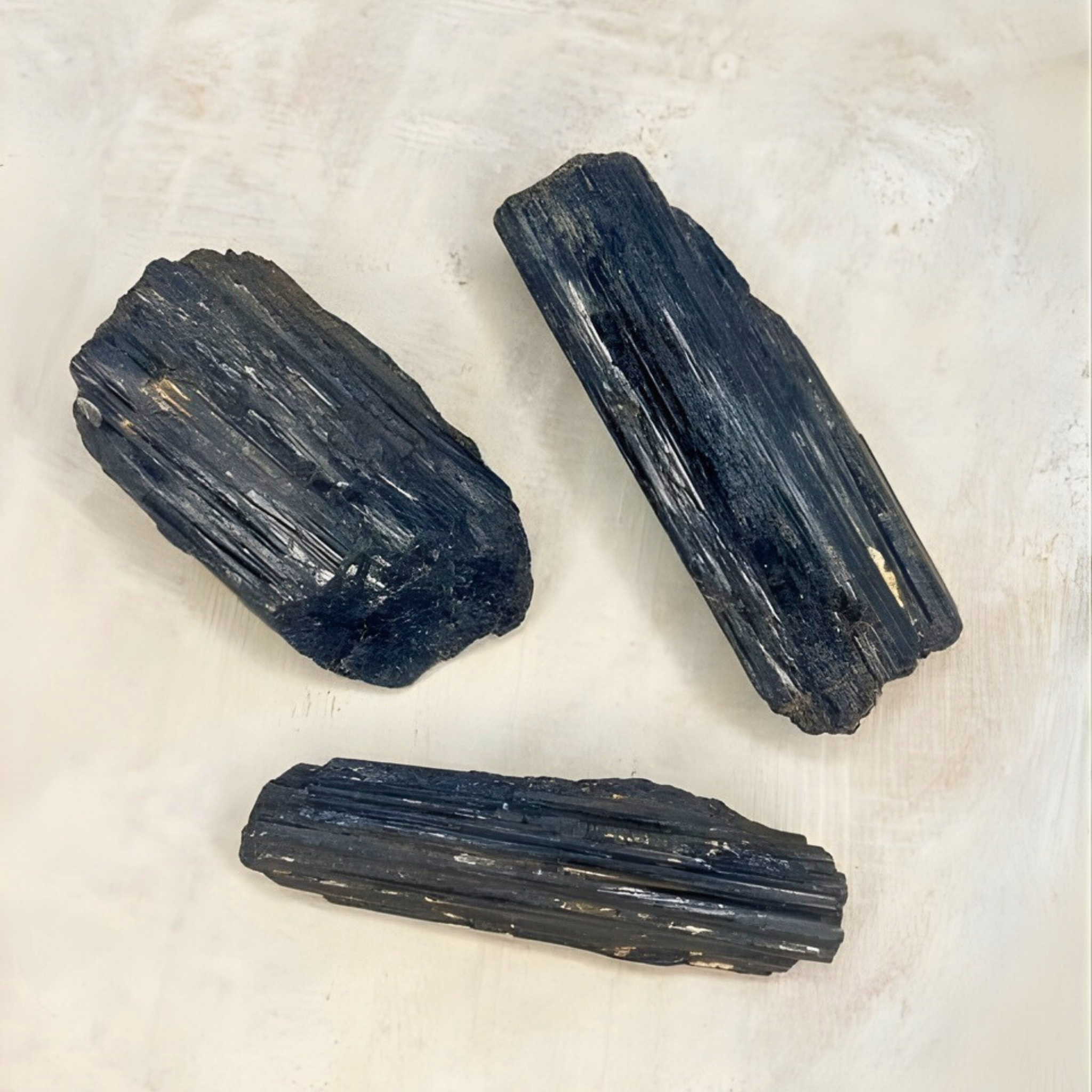 Three black crystals on a light beige background