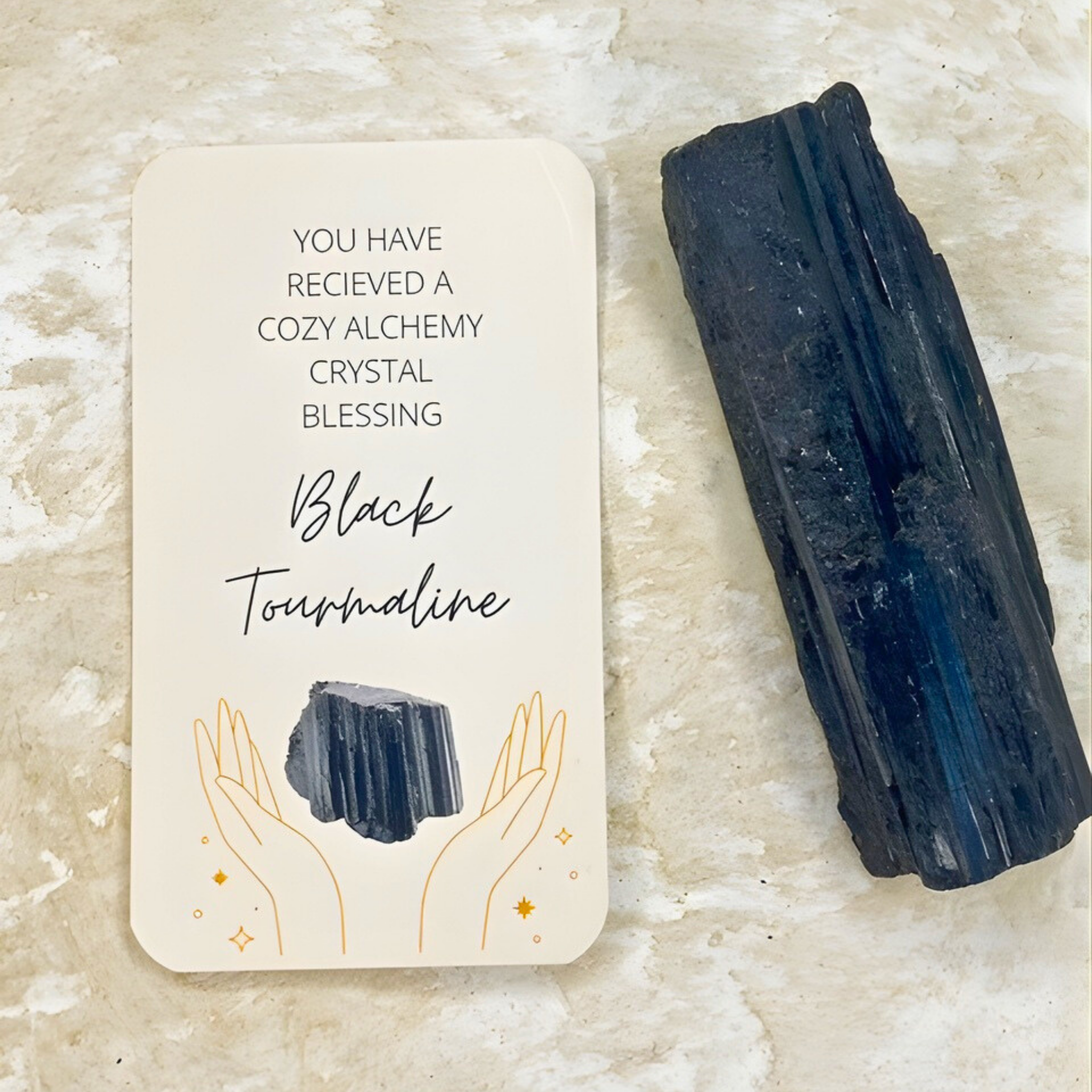 Black tourmaline crystal and blessing card on a textured surface