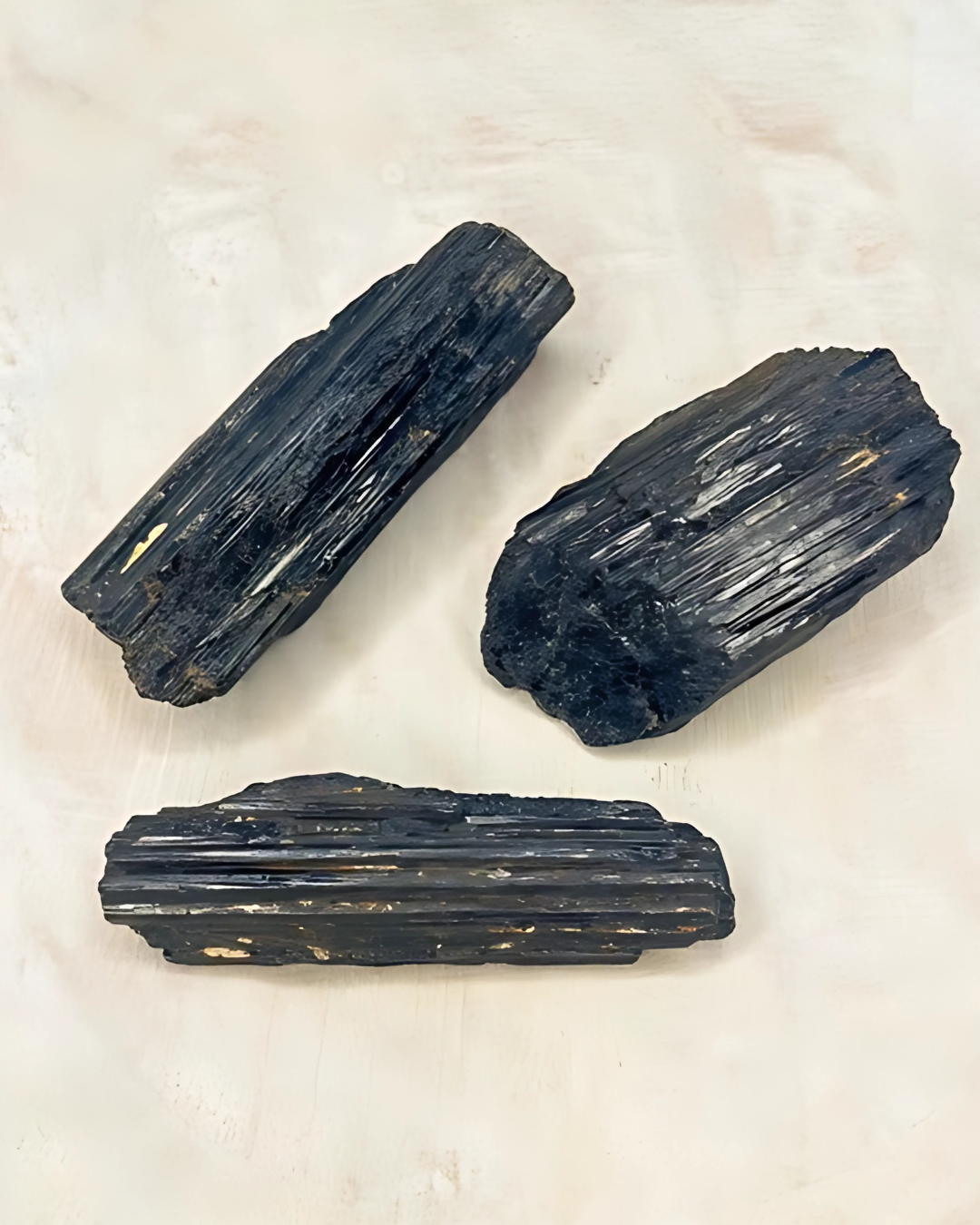 Three black crystals on a light beige background