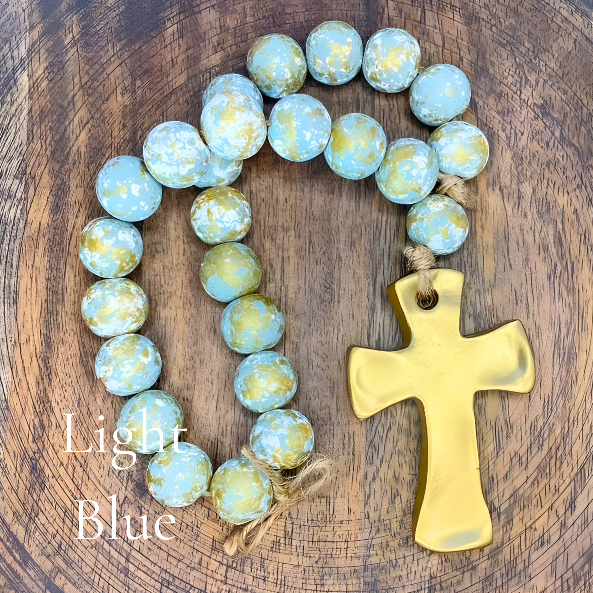 Light blue rosary with a gold cross on a wooden surface