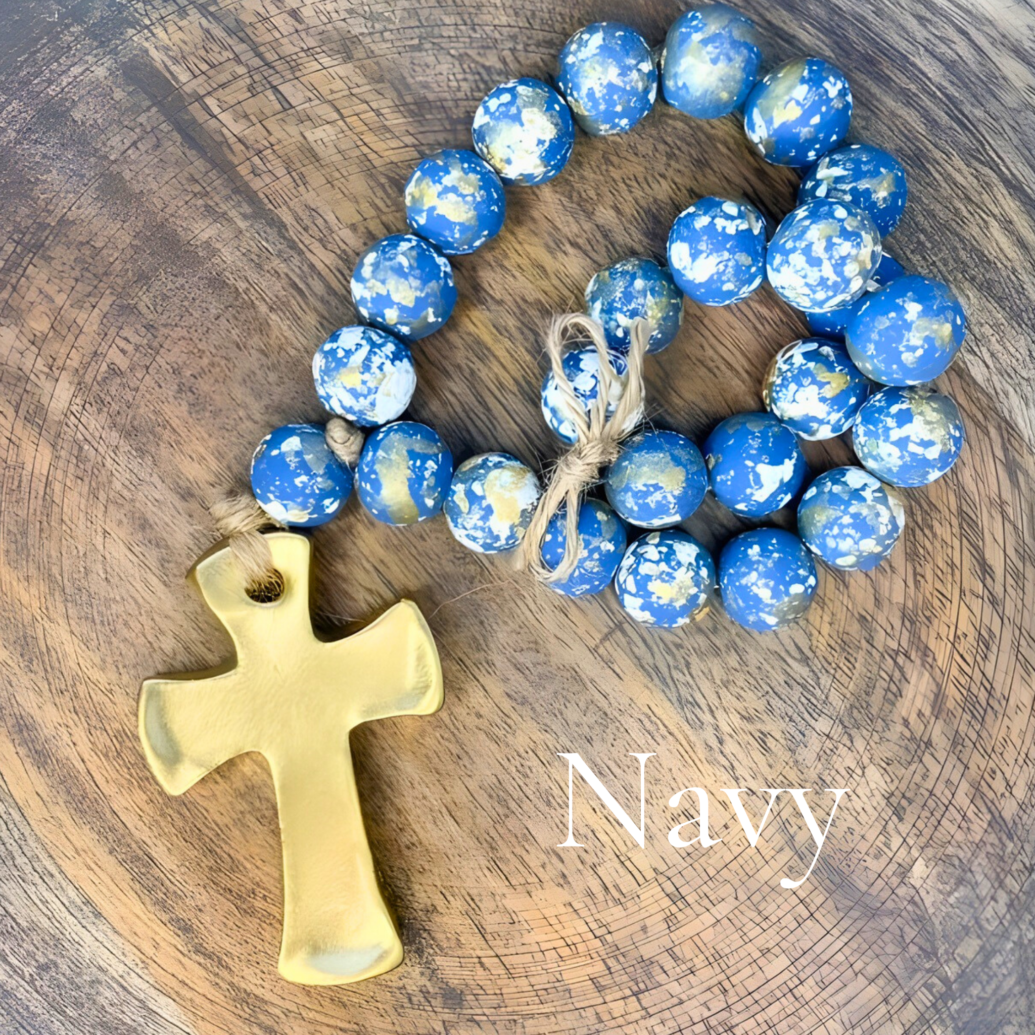 Navy blue beaded bracelet with a gold cross on a wooden surface