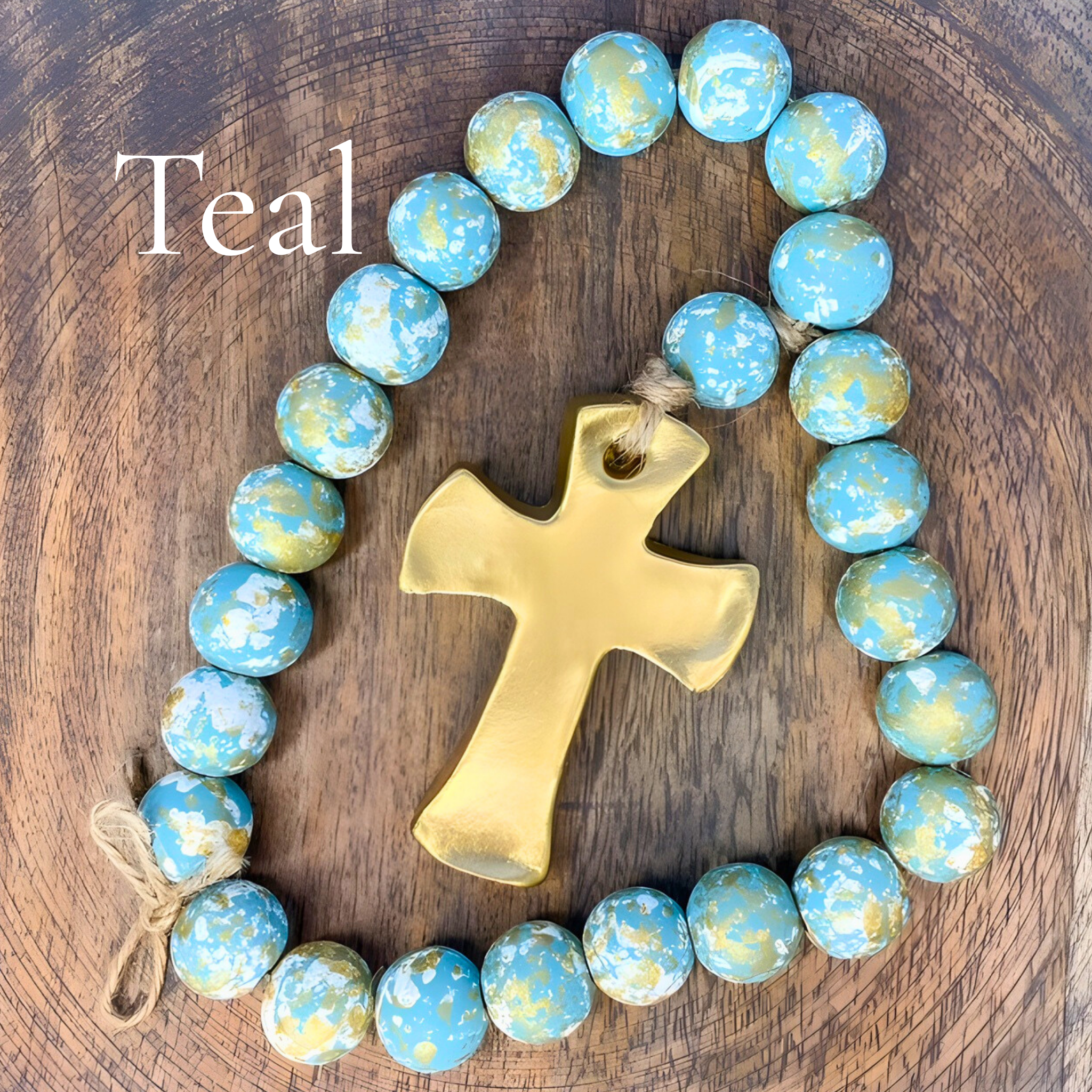 Teal beaded bracelet with a gold cross on a wooden surface, labeled 'Teal'.