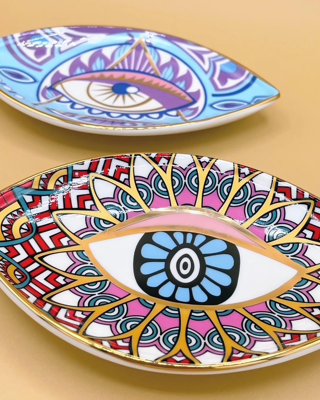 Two decorative plates with eye designs on a beige background