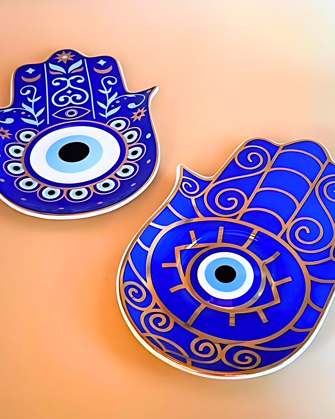Two blue Hamsa hand designs with eye symbol on a peach background