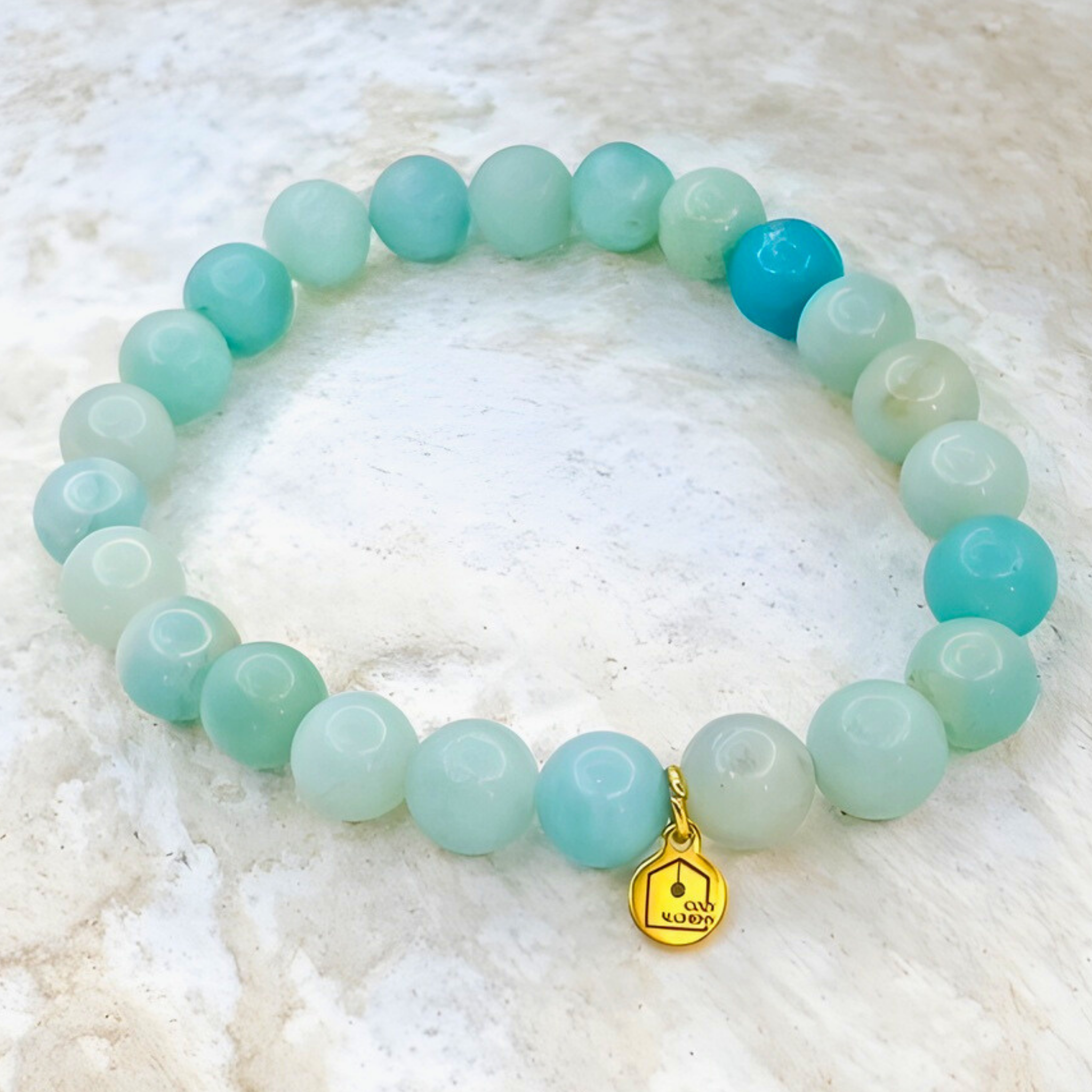 amazonite bead bracelet with charm on rough surface