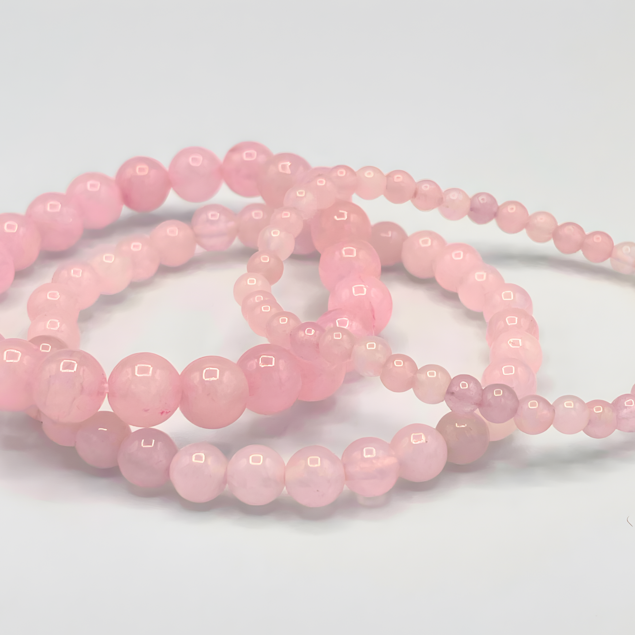 Two strands of pink beads on a light gray background
