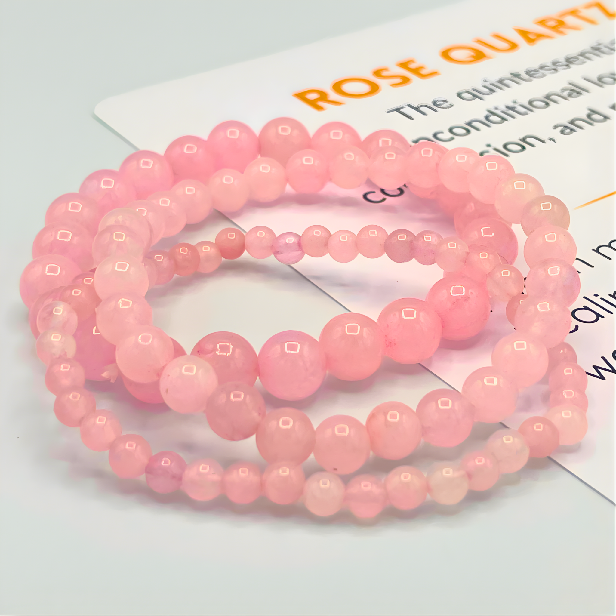 Pink beaded bracelets on a white surface with text in the background