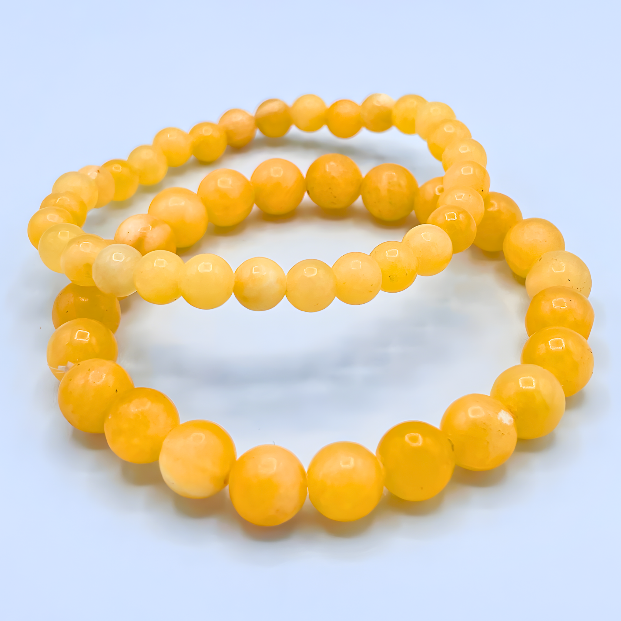 Two yellow beaded bracelets on a light blue background