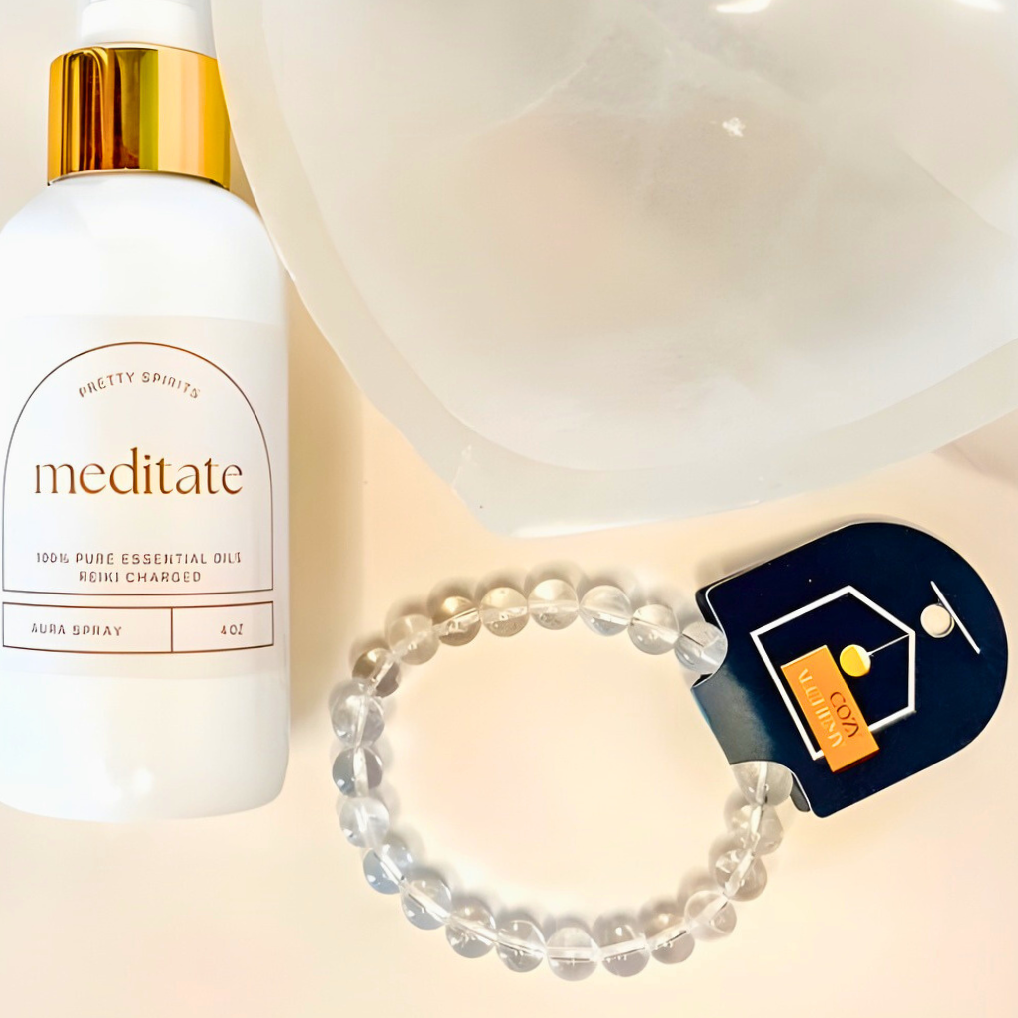 Essential oil spray bottle labeled 'meditate' with a beaded bracelet and card on a light background