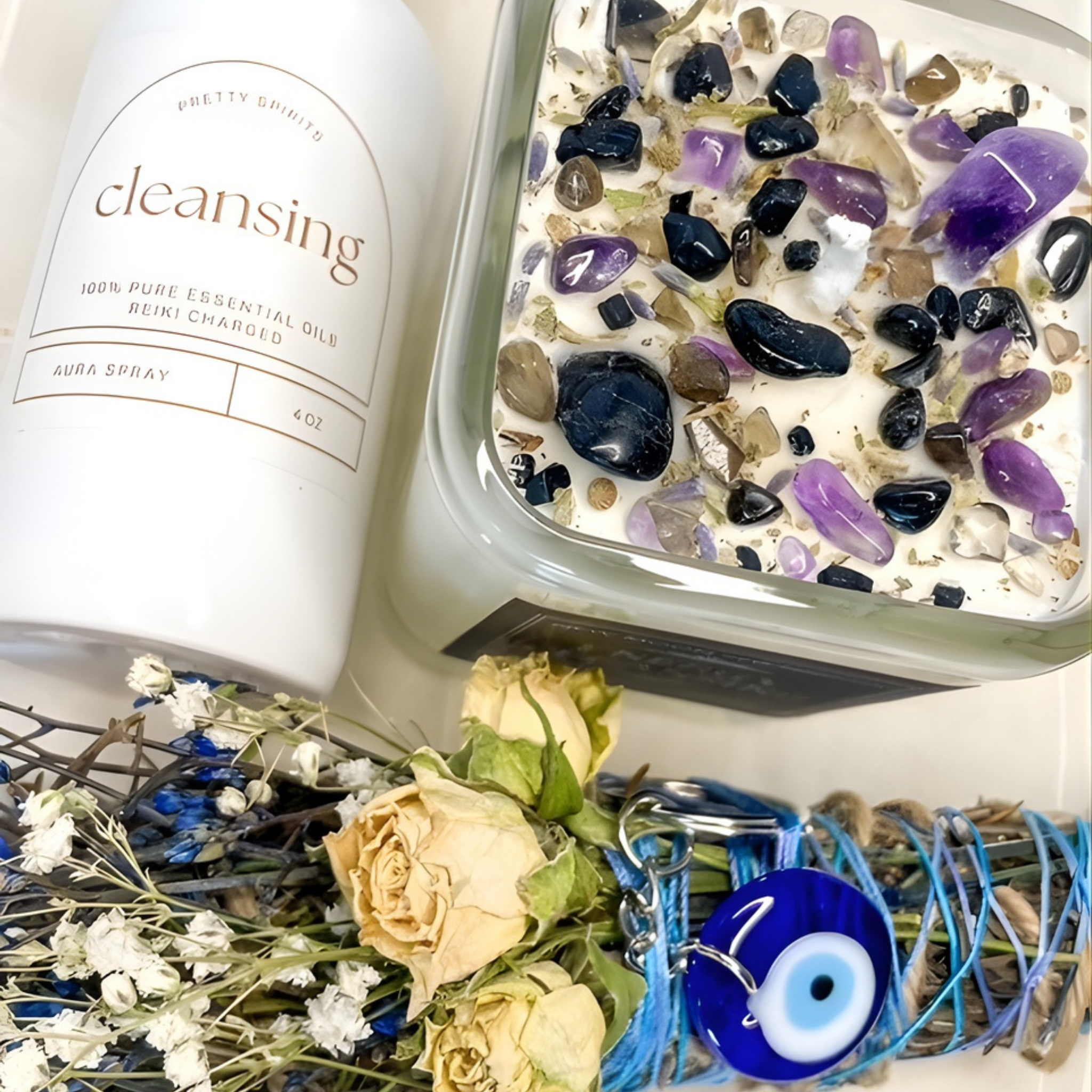 Essential oil spray bottle labeled 'cleansing' with a container of stones and flowers on a wooden surface.