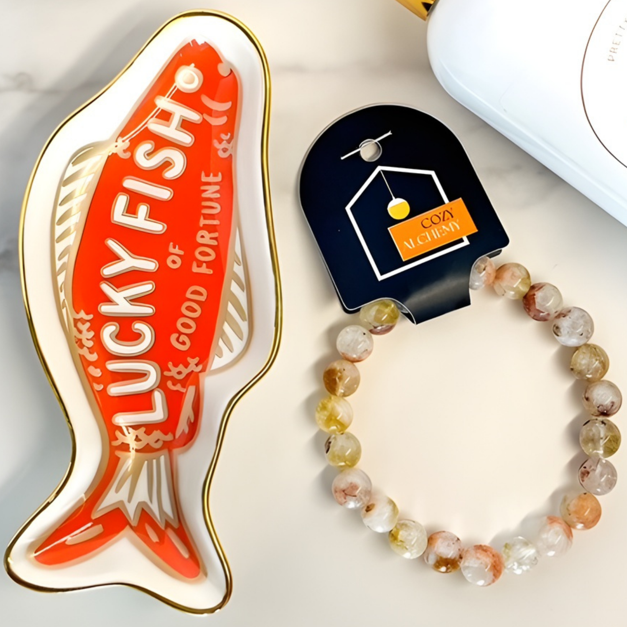 Lucky Fish of Good Fortune enamel pin and beaded bracelet on a white surface