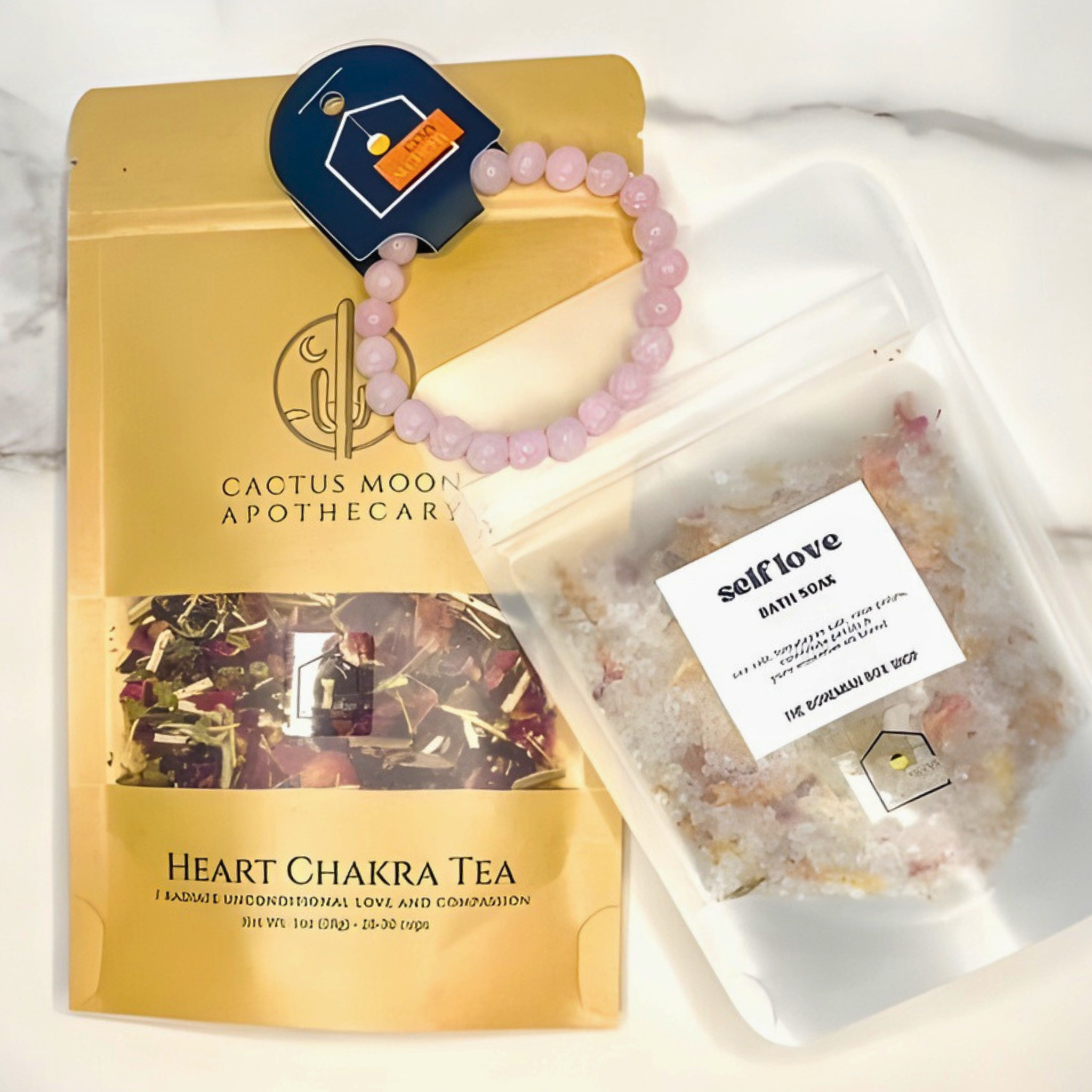 Cactus Moon Apothecary Heart Chakra Tea package, pink bracelet, and self-love bath soaks on a white background