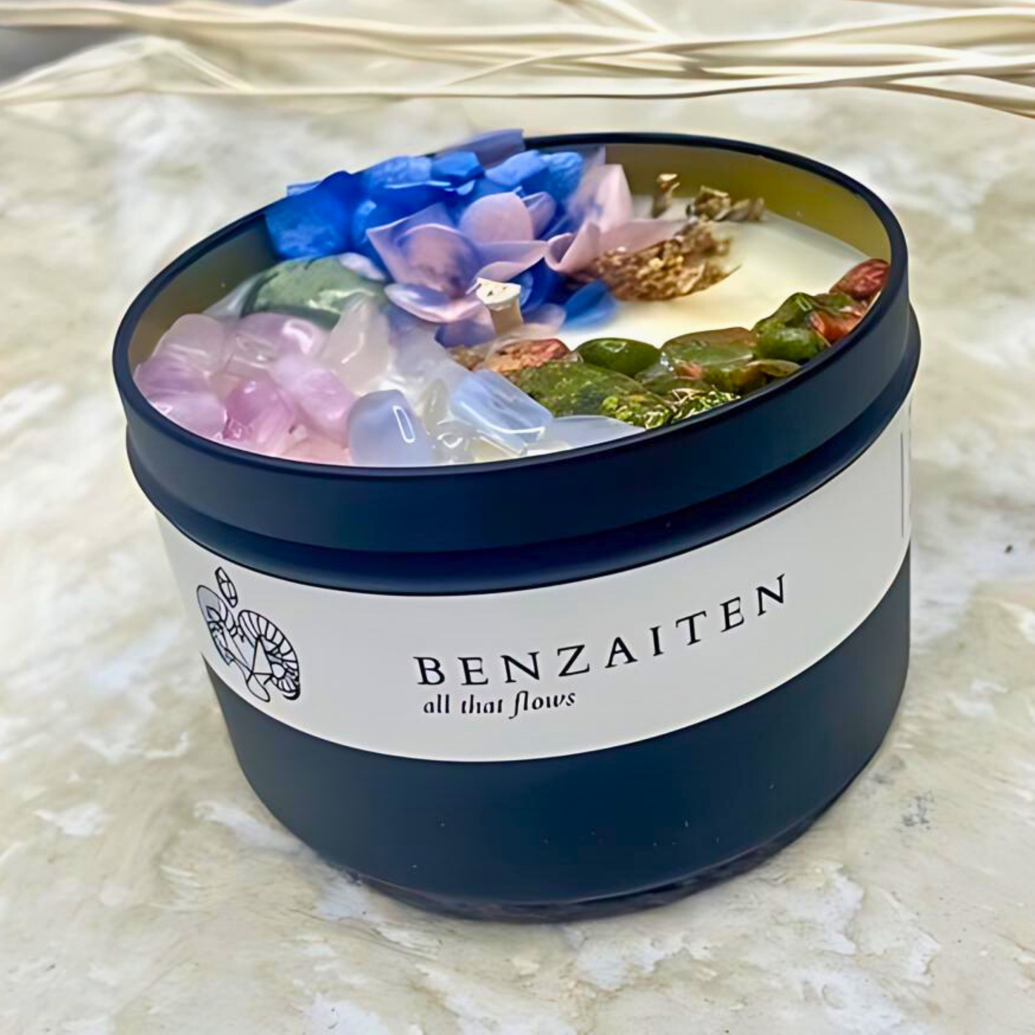 Benzaiten candle with decorative stones and flowers on a marble surface