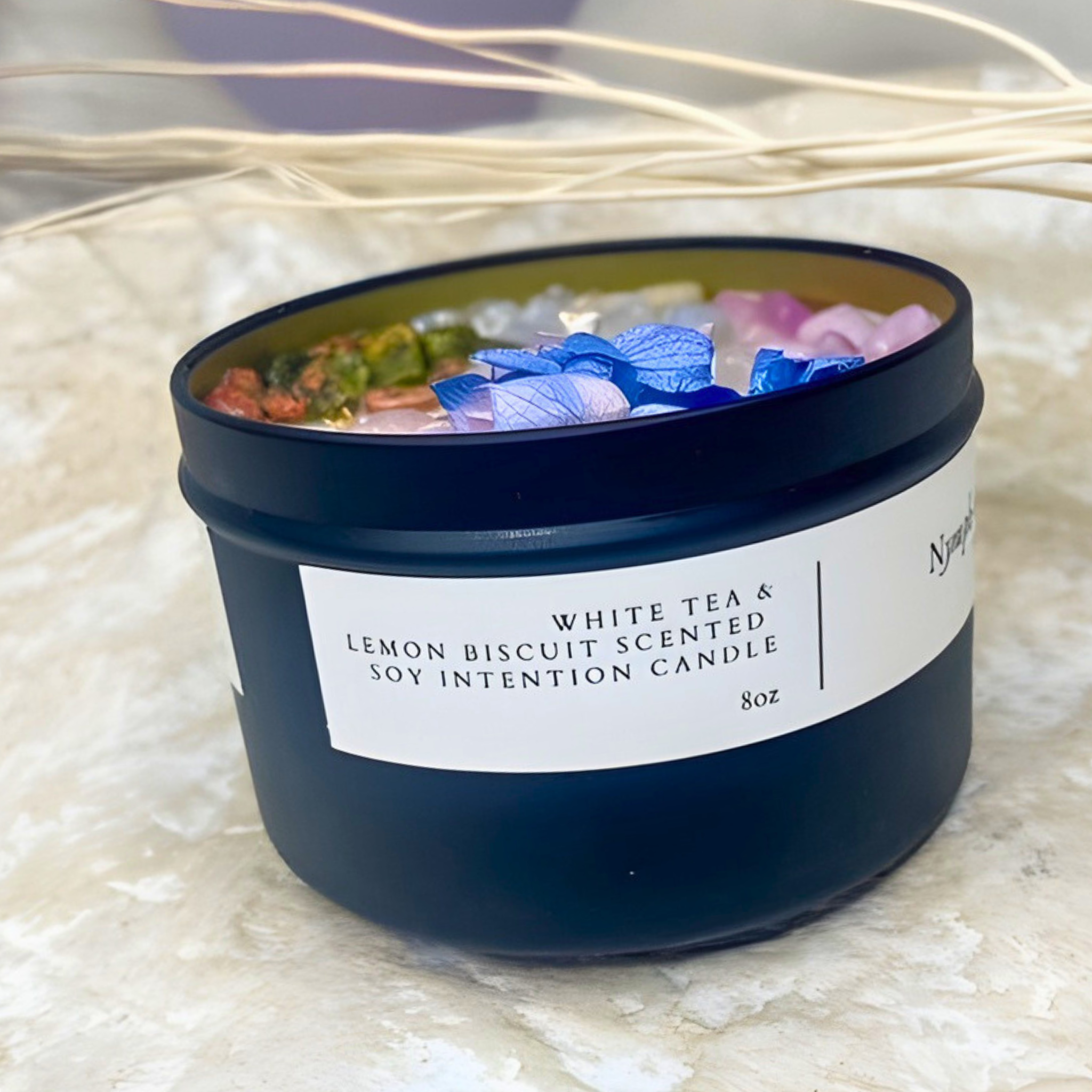 Scented candle with colorful petals on a textured surface