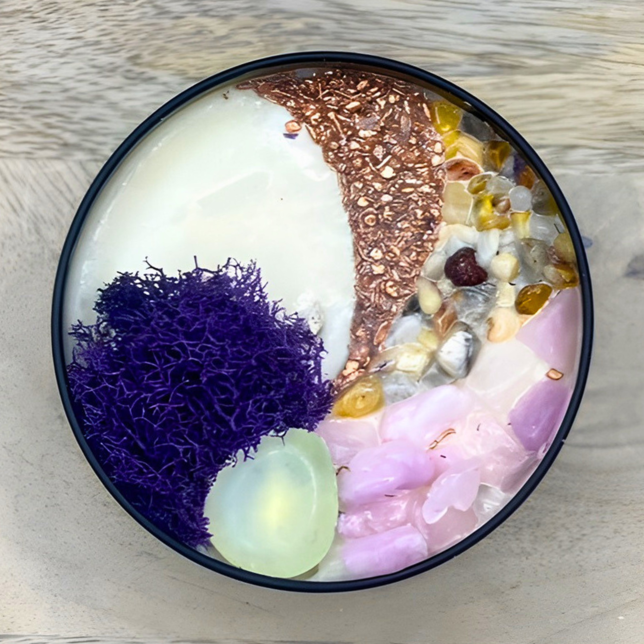 Decorative bowl with purple moss, seashells, and decorative elements on a wooden surface